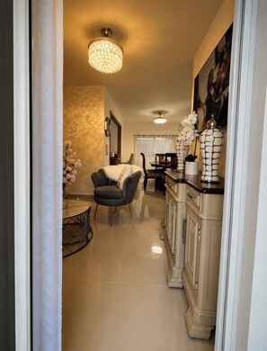 A hallway with a dining area, a chandelier, and a cabinet with decorative items. - Modern, comfortable and safe in SFM with free parking and a (San Francisco de Macorís)