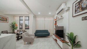 A modern living room with a sofa, TV, dining area, and potted plants. - KOA LIVING (Pucallpa)