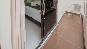 A room with a bed, a chair, a balcony, and a sliding door. - KOA LIVING (Pucallpa)