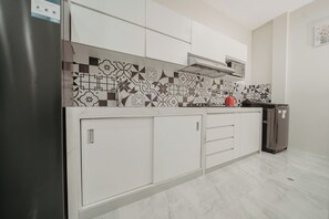 Una cocina moderna con armarios blancos, un salpicadero decorativo y un refrigerador de acero inoxidable.