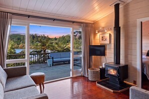 A room with a fireplace, a sofa, a TV, and a view of a lake.