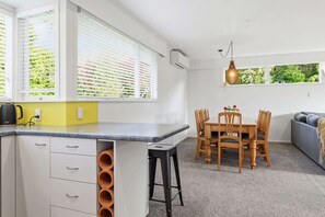 A modern kitchen with white cabinets, a yellow countertop, and a dining area with wooden chairs and a table.