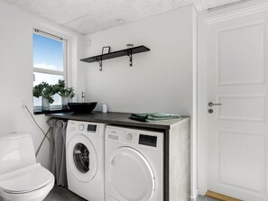 A compact laundry room with a washing machine, dryer, and a shelf above the counter.
