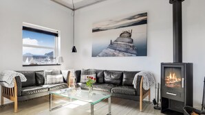 Una sala de estar moderna con una mesa de centro de vidrio, un sofá de cuero, una chimenea y obras de arte en las paredes.