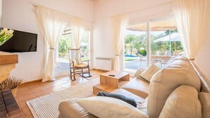 A living room with a sofa, a chair, a TV, and a view of the outdoors. - Nice home in Campos with private swimming pool, can be inside or outside (Campos)