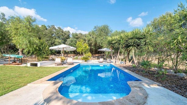 A rectangular swimming pool with a curved edge, surrounded by a concrete deck. There are lounge chairs and umbrellas in the background. - Nice home in Campos with private swimming pool, can be inside or outside (Campos)