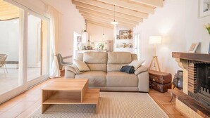 A living room with a sofa, a coffee table, a fireplace, and a view through a glass door. - Nice home in Campos with private swimming pool, can be inside or outside (Campos)