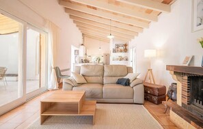 A living room with a sofa, a coffee table, a fireplace, and a view through a glass door. - Nice home in Campos with private swimming pool, can be inside or outside (Campos)