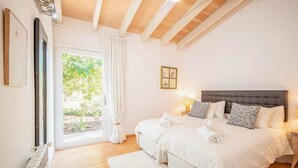 A bedroom with a large bed, a window with curtains, a radiator, and a framed picture on the wall. - Nice home in Campos with private swimming pool, can be inside or outside (Campos)
