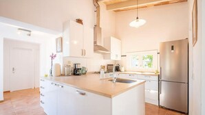 A modern kitchen with white cabinetry, a central island, stainless steel appliances, and a window providing natural light. - Nice home in Campos with private swimming pool, can be inside or outside (Campos)