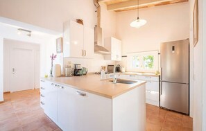 A modern kitchen with white cabinetry, a central island, stainless steel appliances, and a window providing natural light. - Nice home in Campos with private swimming pool, can be inside or outside (Campos)