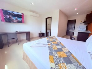 Ein Hotelzimmer mit Bett, Schreibtisch, Stuhl, Fernseher, Küchenzeile und Bad.