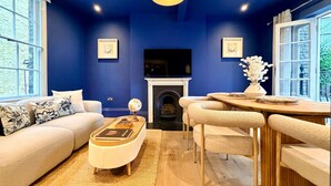 Ein Wohnzimmer mit blauer Wand, Kamin, Sofa, Couchtisch und Essbereich.