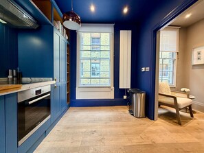 A modern kitchen with a built-in oven, a window with a view, and a seating area with a chair and table. - 2 Mins Walk to The Ritz Mayfair House (London)