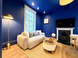 A living room with a sofa, a coffee table, a lamp, a fireplace, and a TV. - 2 Mins Walk to The Ritz Mayfair House (London)