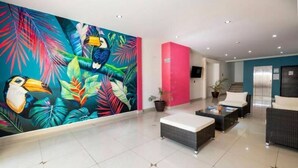 A lobby with a colorful mural, a reception desk, seating area, and a staircase. - Beautiful King-Size Studio with Panoramic View (Playa del Carmen,)