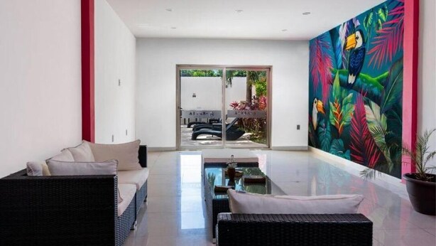 A modern interior with a sofa, a dining table, and a large tropical mural. - Beautiful King-Size Studio with Panoramic View (Playa del Carmen,)