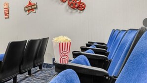 Cine con filas de asientos negros, un cubo de palomitas y decoraciones temáticas de películas.