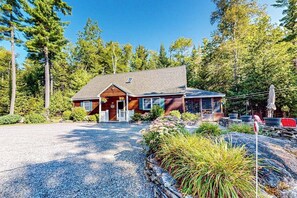 Ein zweistöckiges Haus mit Kiesweg, umgeben von dichtem Wald.