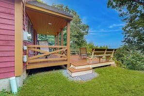 A wooden deck with a covered seating area, a gate, and a building with a red exterior.