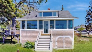 Una casa de dos pisos con un balcón, una escalera y un ventanal grande.