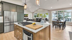 Una cocina moderna con una isla central, electrodomésticos de acero inoxidable y un comedor con vistas.