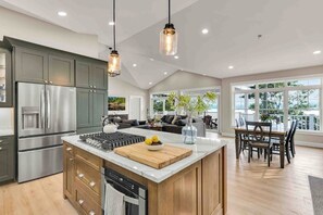 Een moderne keuken met een centraal eiland, roestvrijstalen apparatuur en een eetgedeelte met uitzicht.