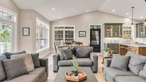 Un espacio habitable amplio con un conjunto de sofás, una mesita de centro con una planta y una cocina al fondo.
