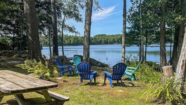 Un cadre idyllique au bord du lac, avec une table de pique-nique et des fauteuils Adirondack.
