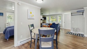 Un intérieur moderne comprenant un coin repas, un salon avec un canapé et une cuisine à l’arrière-plan.
