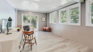 Une pièce spacieuse avec une grande fenêtre, un bureau avec une chaise et une petite table avec une chaise.