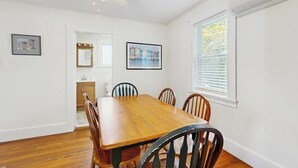 Ein Esszimmer mit Holztisch und -stühlen, einem Deckenventilator und gerahmten Bildern an den Wänden.