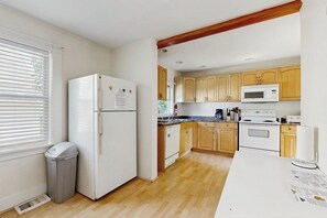 Une cuisine avec des meubles de rangement en bois, un réfrigérateur blanc, un four à micro-ondes et une cuisinière.