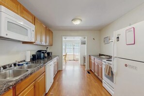 A kitchen with wooden cabinets, a microwave, a refrigerator, and a sink.