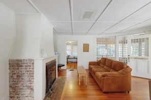 A living room with a fireplace, a brown sofa, a wooden coffee table, and a door with a 'Welcome' sign.