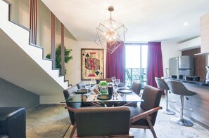 A modern dining area with a glass table, chairs, and a geometric chandelier. - El Semillero (Monterrey)