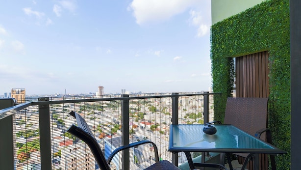 A balcony with a glass table and chairs, a view of the cityscape, and a green wall. - El Semillero (Monterrey)