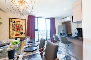 A modern dining area with a glass table, chairs, and a view of the city. - El Semillero (Monterrey)
