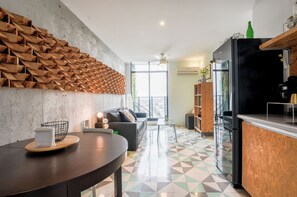Une cuisine moderne avec un réfrigérateur noir, des meubles de rangement en bois et un coin repas comprenant une table ronde et des chaises.