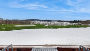A snow-covered outdoor area with a wooden deck and a view of a distant landscape.