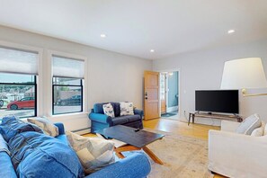 A modern living room with a sofa, a coffee table, a TV, and a lamp. - Waterfront, walkable home with beautiful kitchen & washer/dryer - dog-friendly (Camden)