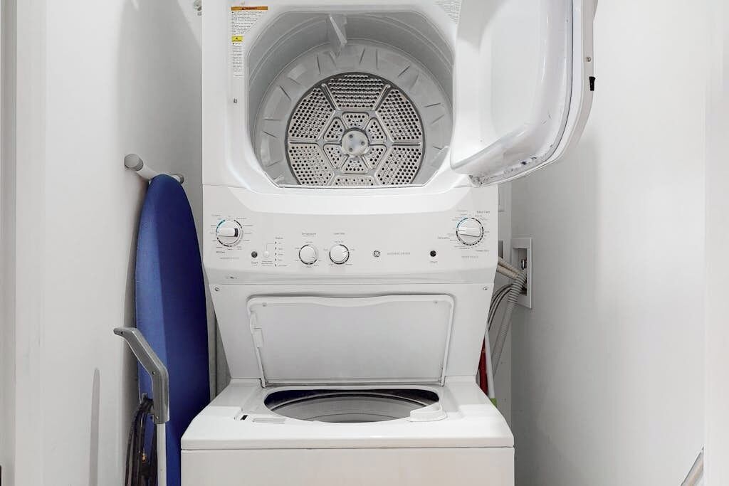A front view of a white washing machine with a control panel, a blue towel, and a metal handle.