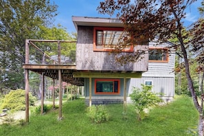 Ein zweistöckiges Holzhaus mit Balkon, umgeben von viel Grün.