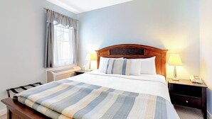 Une chambre d’hôtel avec un lit, des lampes de chevet, une fenêtre avec des rideaux et un ventilateur de plafond.