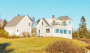 Ein zweistöckiges Haus mit einem großen Balkon, einer Garage und einem gepflegten Rasen.