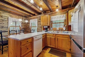 A rustic cabin-style kitchen with wooden cabinets, a white countertop, and a stainless steel refrigerator. - Lakefront home w/ pristine views Outdoor firepit and full kitchen (Greenville)