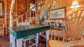 Un intérieur rustique en bois, avec une table à manger, des chaises, une bibliothèque et un fauteuil décoratif.