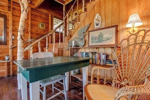 A rustic wooden interior with a dining table, chairs, a bookshelf, and a decorative chair. - Historic Home with Large Deck, Free WiFi, Washer/Dryer - Near Beach and Downtown (Boothbay Harbor)