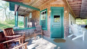 Une cabane en bois avec une véranda, des sièges d’extérieur et une porte.