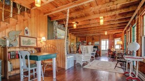 L’intérieur d’un chalet en bois comprend un coin repas, des étagères et un escalier.